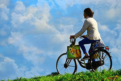 Lady riding a bicycle across a field